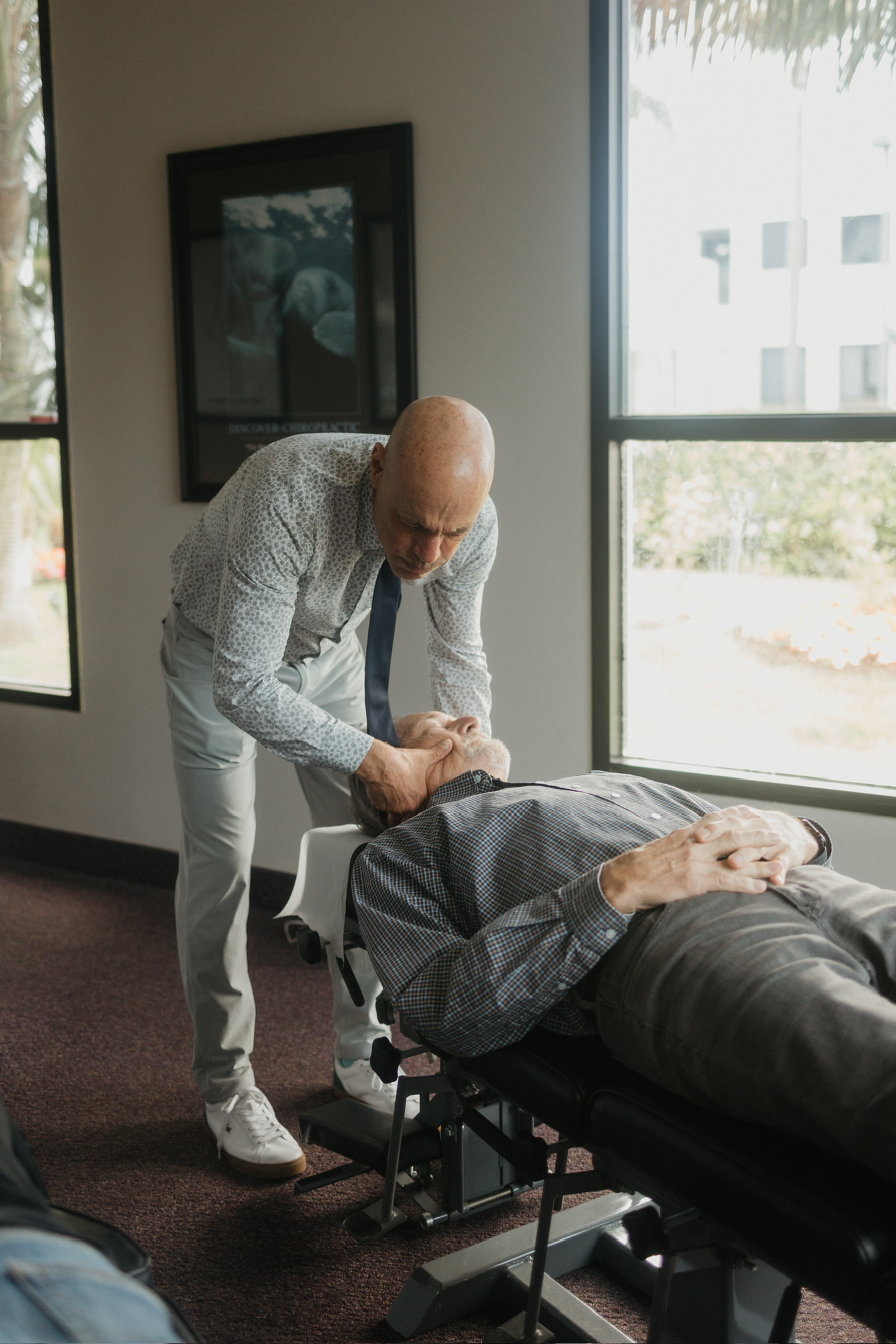 Dr. Billy DeMoss treating an older patient&rsquo;s neck at the Newport Beach office
