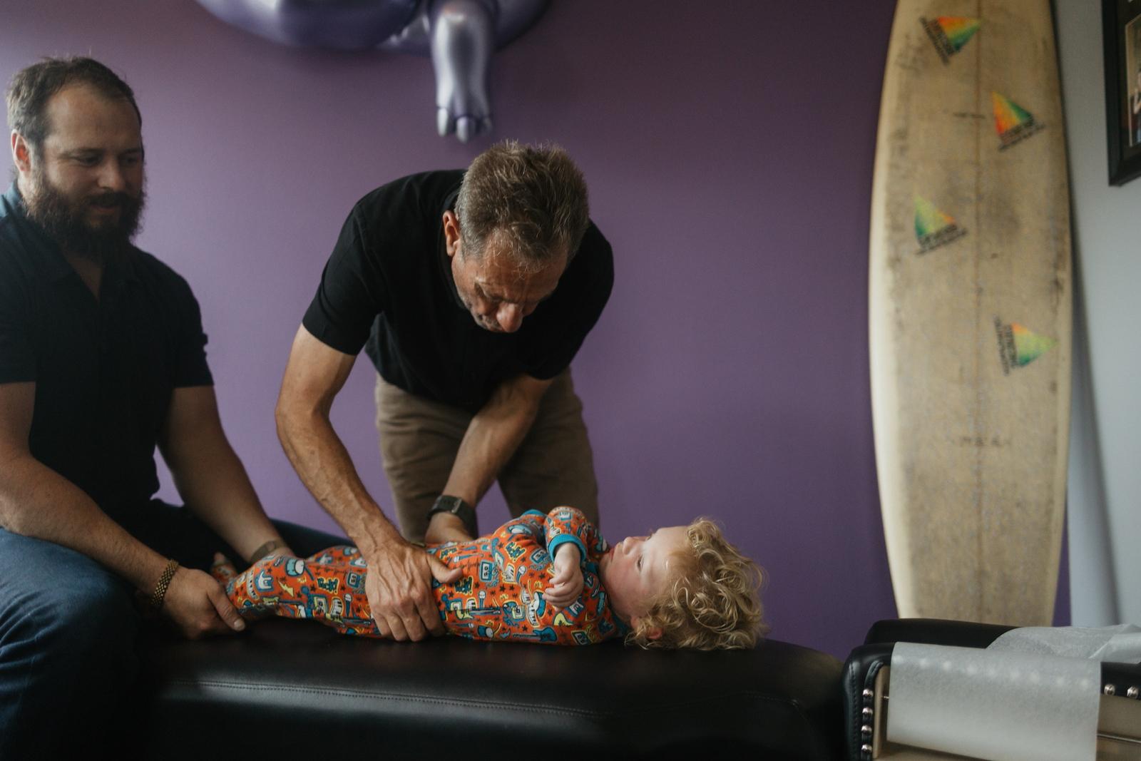 A child being adjusted at DeMoss Chiropractic while a parent looks on